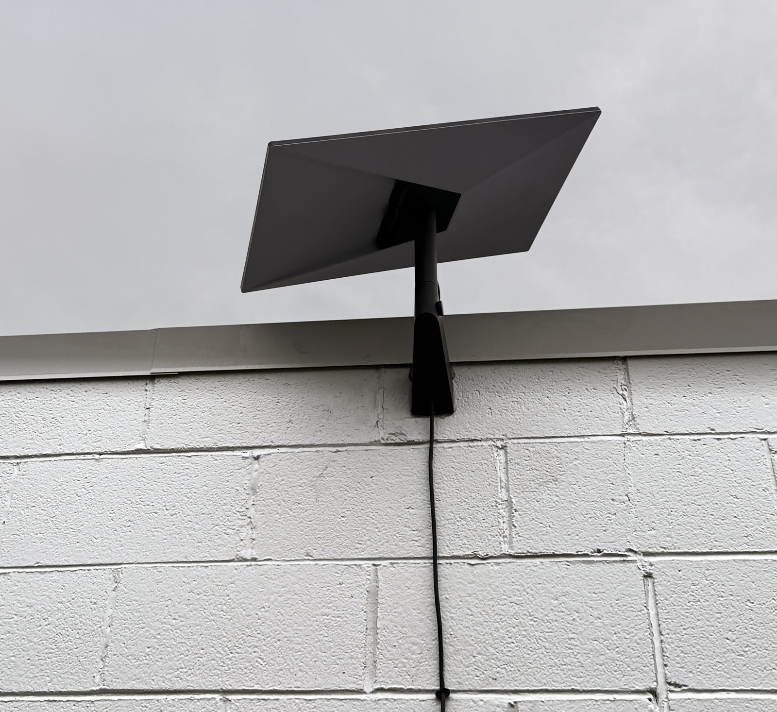 Starlink dish on a wall mount with the cable run neatly down the wall